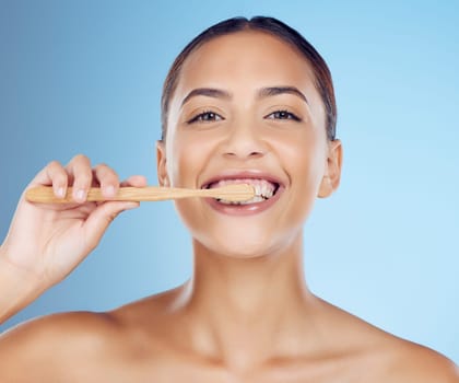 Teeth, woman and portrait of bamboo toothbrush for dental wellness, healthy cleaning or beauty cosmetics. Happy female, eco wooden brush and toothpaste of mouth, face smile and studio blue background.