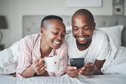 Black couple in bed with phone, coffee and happiness with morning routine, social media or streaming online. Wifi, communication and technology with happy man and woman, relax at home together.