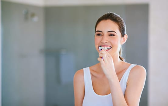 Toothbrush, toothpaste and woman brushing teeth in bathroom for health, happiness and wellness in morning. Girl, cleaning mouth for dental care and oral hygiene or smile in home with mockup space.