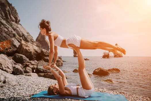 Woman sea yoga. Back view of free calm happy satisfied woman with long hair standing on top rock with yoga position against of sky by the sea. Healthy lifestyle outdoors in nature, fitness concept.