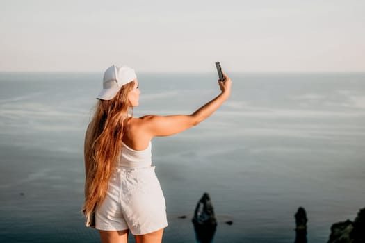 Woman travel sea. Young Happy woman in a long red dress posing on a beach near the sea on background of volcanic rocks, like in Iceland, sharing travel adventure journey