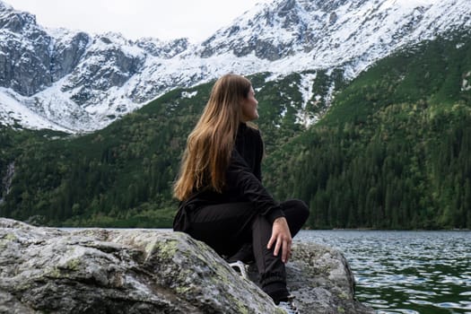 Young woman enjoying nature in Morskie Oko Snowy Mountain Hut in Polish Tatry mountains Zakopane Poland. Naturecore aesthetic beautiful green hills. Mental and physical wellbeing Travel outdoors tourist destination