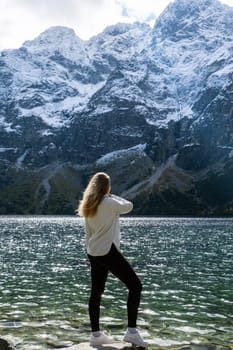 Young woman enjoying nature in Morskie Oko Snowy Mountain Hut in Polish Tatry mountains Zakopane Poland. Naturecore aesthetic beautiful green hills. Mental and physical wellbeing Travel outdoors tourist destination