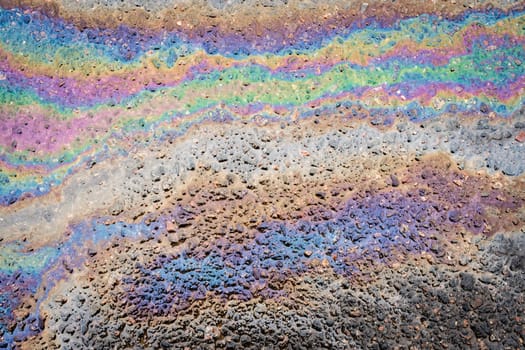 The texture of gasoline stains on the asphalt close-up. Gasoline spilled onto the road.