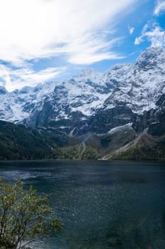 Morskie Oko lake Snowy Mountain Hut in Polish Tatry mountains, Zakopane, Poland. Beautiful green hills and mountains in dark clouds and reflection on the lake Morskie Oko lake. Travel tourist destination