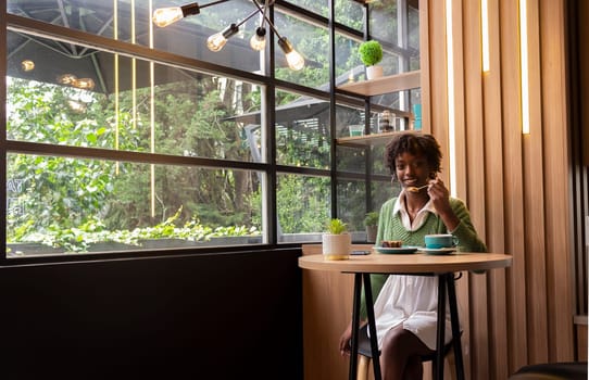 copyspace of young african model having a cake and tea sitting in a restaurant enjoying her lifestyle. High quality photo