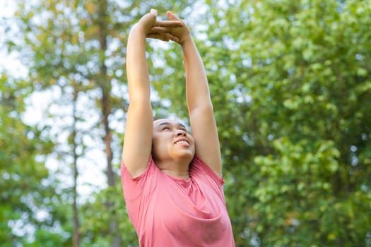 Young Asian woman in sportswear stretches before exercising in the park for a healthy lifestyle. Young healthy woman warming up outdoors. Healthy lifestyle concept.