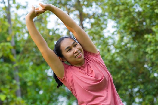 Young Asian woman in sportswear stretches before exercising in the park for a healthy lifestyle. Young healthy woman warming up outdoors. Healthy lifestyle concept.