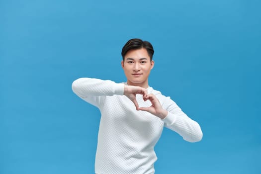 young cheerful guy happy positive smile show fingers heart sign love feelings 