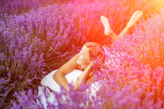 Woman lavender field. A middle-aged woman lies in a lavender field and enjoys aromatherapy. Aromatherapy concept, lavender oil, photo session in lavender.