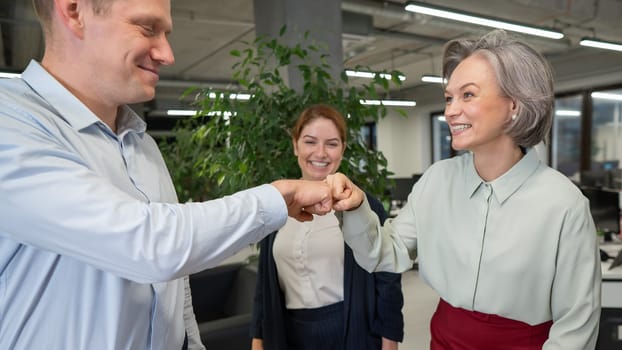 Caucasian man bumping his fists with colleagues as a sign of success
