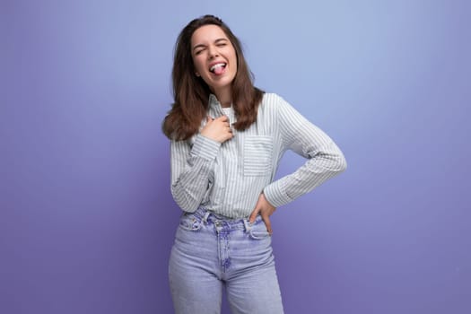 funny young brunette woman in shirt with grimace on studio background.