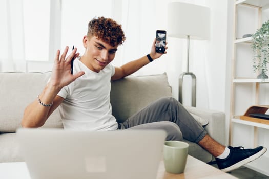man interior message sofa smart selfies phone student smartphone sports young internet couch lifestyle technology curly teenager person cyberspace cellphone mobile home