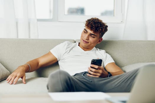 man interior cellphone curly mockup young teenager modern using couch sofa blogger technology phone online message internet business male laptop sports