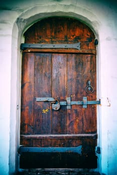 Vintage wooden door with an old rusty padlock. Ancient door in a stone doorway. Vintage camera filter added to image