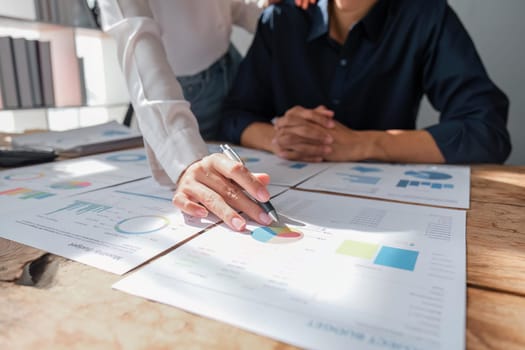 business woman is helping to husband to analyze business . They are analyzing data from graphic charts.