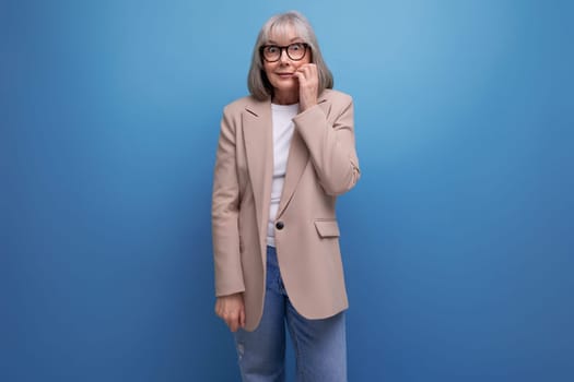 a middle-aged business woman in a stylish look stands thoughtfully on a studio background with copy space.