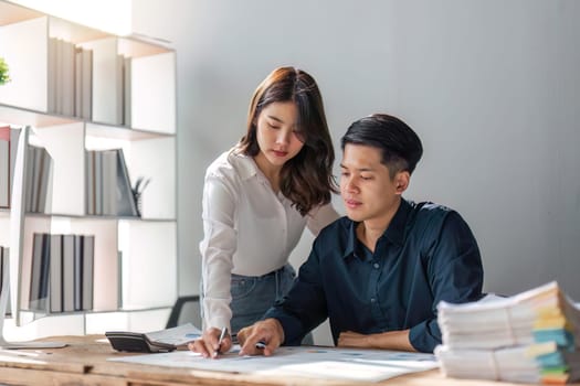 business woman is helping to husband to analyze business . They are analyzing data from graphic charts.