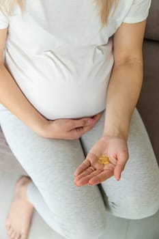 Pregnant woman drinks omega three. Selective focus. White.