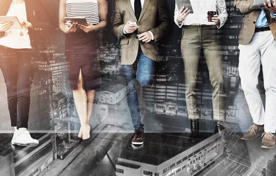 Getting their feet into the door of business. Cropped studio shot of a group of businesspeople using wireless technology while waiting in line against a gray background