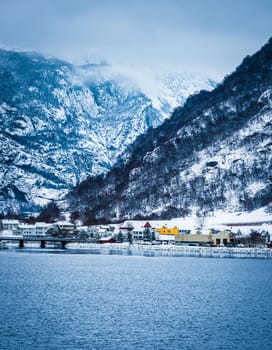 wooden houses on the banks of the Norwegian fjord, beautiful mountain landscape in winter