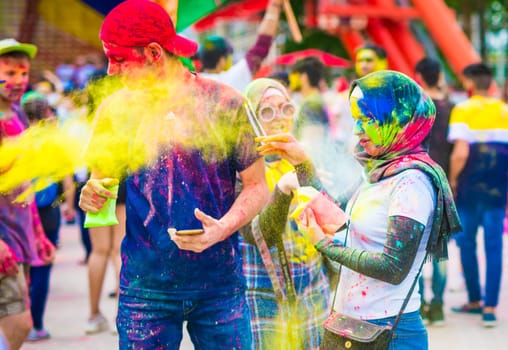 Khakiv, Ukraine - 19 May 2018: People sprinkle colorful paints during the festival. People with colorful faces celebrating holi fest