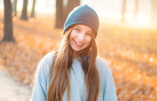 Happy girl with headphones in autumn park