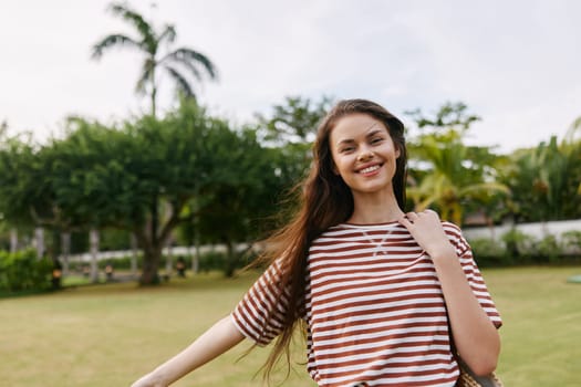 woman sunny carefree walk enjoy nature bag natural grass portrait joy striped freedom park summer t-shirt active smiling lifestyle beautiful happiness