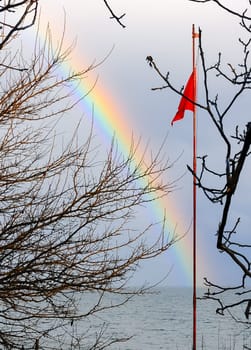 Red flag on the background of a multi-colored rainbow over the sea, the Black Sea
