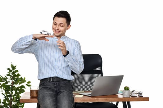 Successful caucasian businessman holding a toy car while standing at desk. Car dealerships offer car . Car insurance