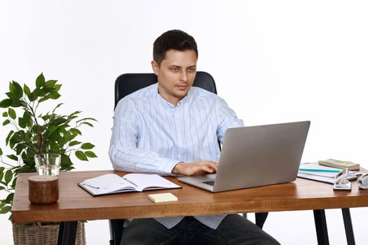 young man using laptop computer for online work at table on white background