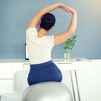 Rearview shot of a young businesswoman stretching while working at home.