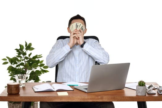 happy businessman using laptop and holding money while sitting on chair at desk.