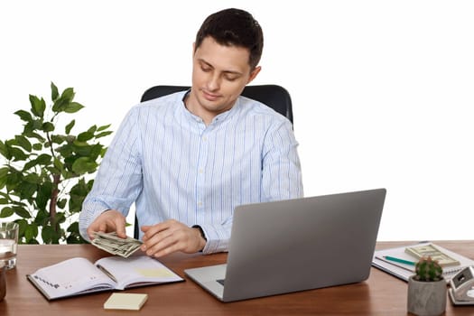 young handsome entrepreneur man working on laptop and holding money while sitting on chair at desk.