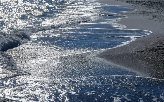 Bright reflections on the water on a sunny day on the sandy shore of the Black Sea