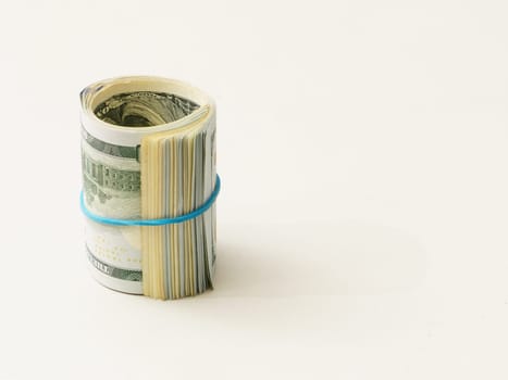 A stack of one hundred dollar bills tied with a blue rubber band on a white background.