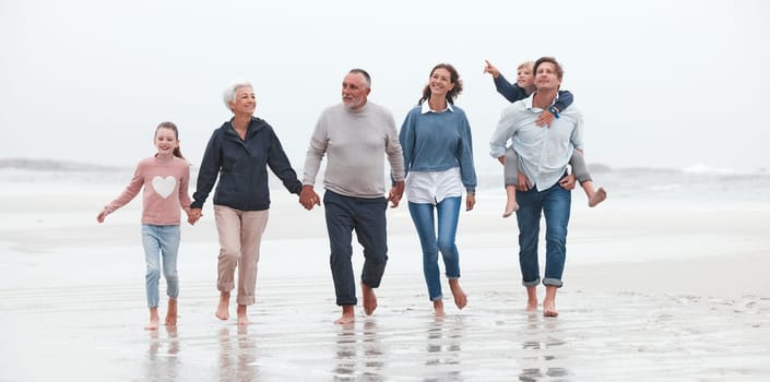Family, beach and children with grandparents, parents and kids walking in the water on the sand in a summer holiday. Travel, love and vacation with a girl, boy and relatives taking a walk by the sea.