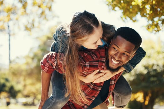 Piggy back, couple and love in park, smile and happy on date, romance and fun together in spring nature. Interracial man and woman happiness, play or relationship outdoor in forest, care or woods.