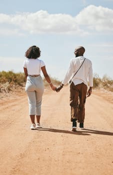 Black couple, love and holding hands back view in nature walking on vacation on desert, sand or dirt road. Romance, safari and man, woman and bonding, care or spending time together on outdoors date