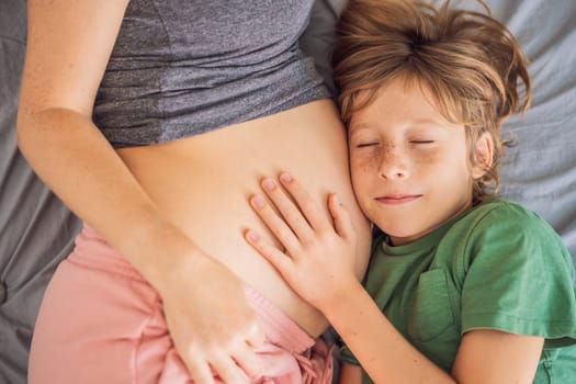 Young beautiful pregnant woman and eldest son. The cute boy leaned his ear against his mother's belly. Expecting a baby in the family concept. Preparing an older child for a younger one.