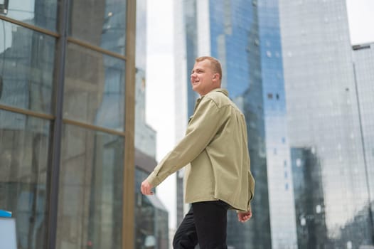 A happy man stands against the backdrop of a skyscraper with his arms spread out to the sides like wings