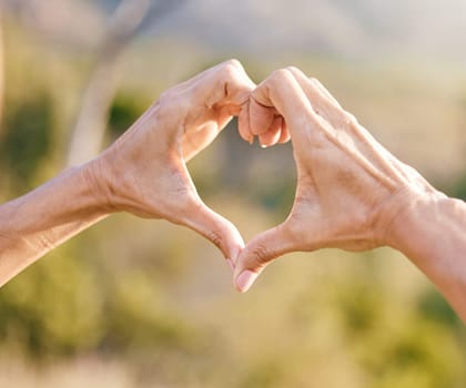 Hands, heart and woman with a love symbol in nature in garden while on adventure, vacation or trip. Freedom, romance and hand romantic gesture with shape emoji in the park, forest or woods on holiday.