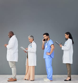Doctors standing in a row isolated on wall background with tablet, phone call and medical paperwork for hospital. Healthcare people or nurse technology in waiting room for clinic or hiring research.