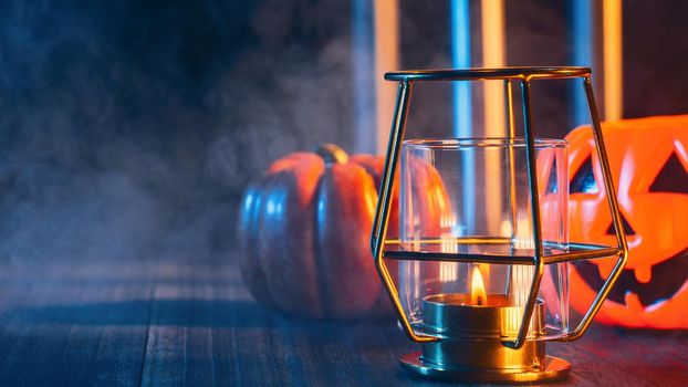 Halloween concept, spooky decorations with lighting up candle and candle holder with blue tone smoke around on a dark wooden table, close up.