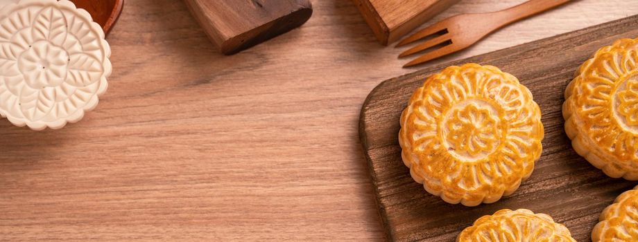 Round shaped moon cake Mooncake - Chinese style pastry during Mid-Autumn Festival / Moon Festival on wooden background and tray, top view, flat lay.