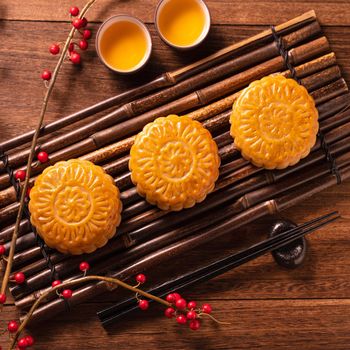 Moon cake Mooncake table setting - Chinese traditional pastry with tea cups on wooden background, Mid-Autumn Festival concept, top view, flat lay.