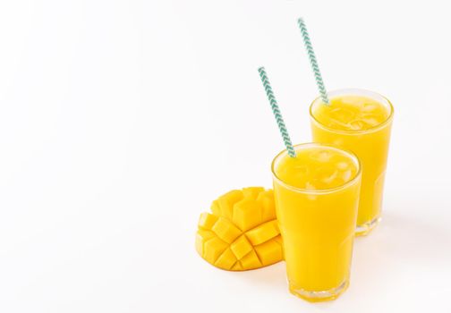 Fresh tropical mango juice with beautiful diced pulp and striped paper straw isolated on white background table, close up, cut out, clipping path.