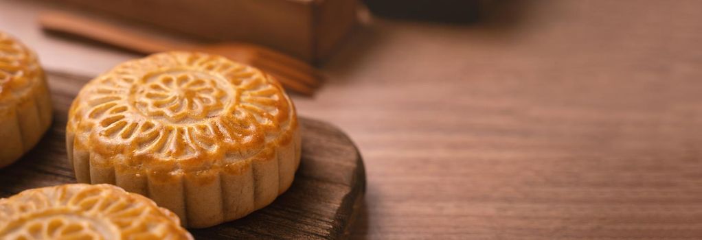 Round shaped moon cake Mooncake - Chinese style traditional pastry during Mid-Autumn Festival / Moon Festival on wooden background and tray, close up