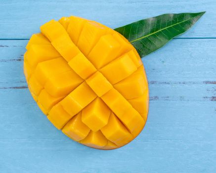 Fresh mango, beautiful chopped fruit with green leaves on dark wooden table background. Tropical fruit design concept. Flat lay. Top view. Copy space