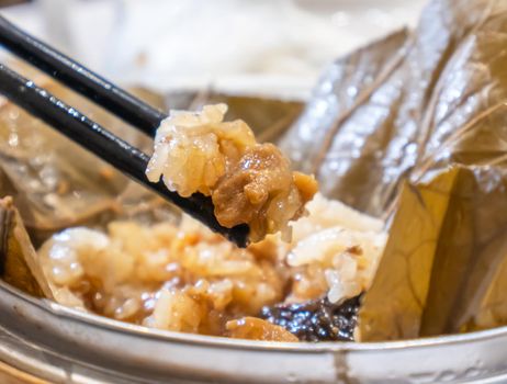 Delicious Lo Mai Gai dim sum, fresh steamed glutinous rice with chicken roll wrapped by lotus leaf in bamboo steamer in hong kong yumcha restaurant.